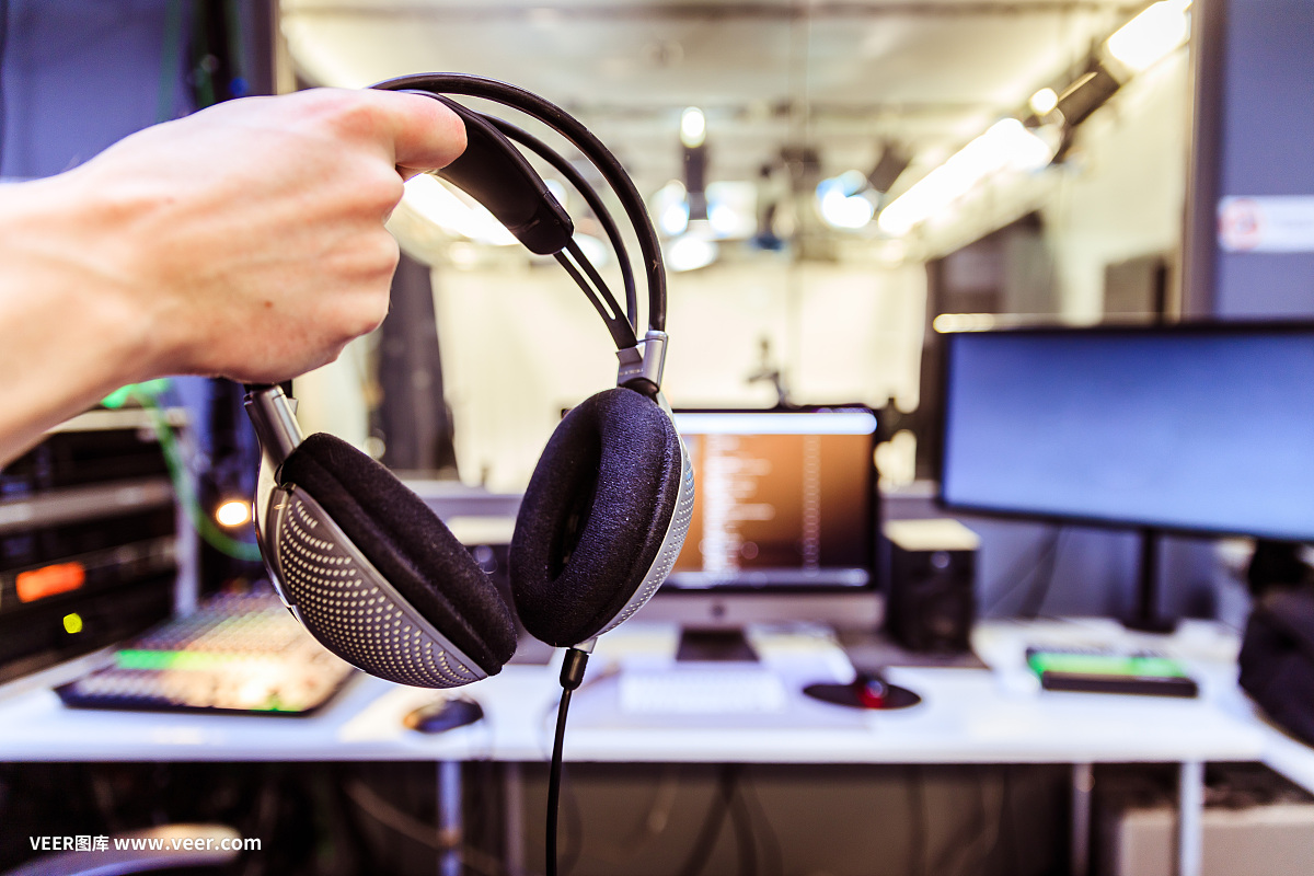 錄音室錄音:一個戴著耳機的年輕人正坐在錄音室里,錄音室的背景模糊不清